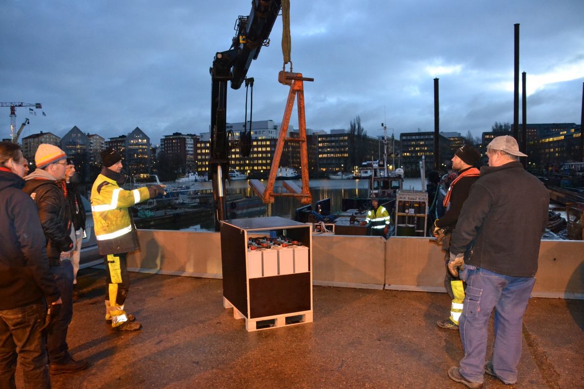 Mit dem ersten Tageslicht beginnt in einem Industriehafen die Verladung des Eqipments auf einen Arbeitsponton mit eigenem Kran. Als erstes die Batterien, die den Stern imt Strom versorgen. Beginn Verladung