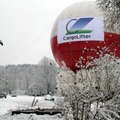 Ein großer, runder Ballon mit der Aufschrift "CargoLifter" steht in einer verschneiten Landschaft. Umgeben von schneebedeckten Pflanzen und Bäumen ist die Szene winterlich. 